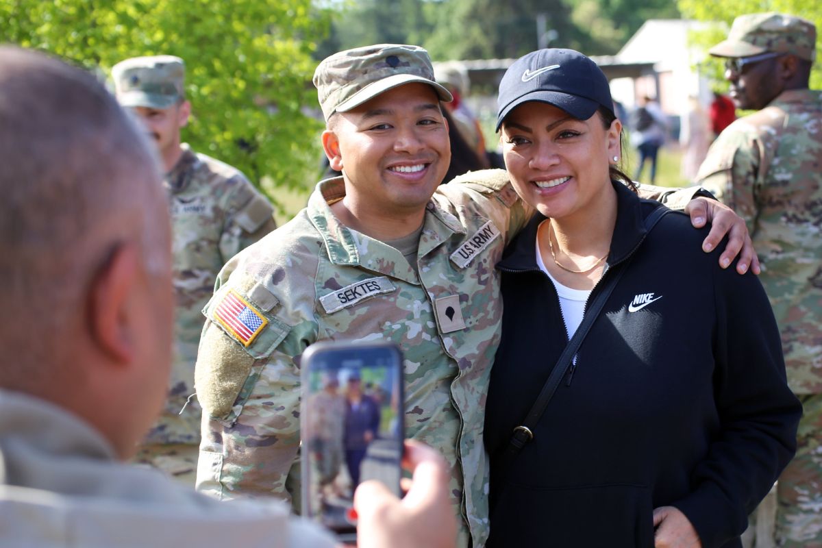 two children hug a service member