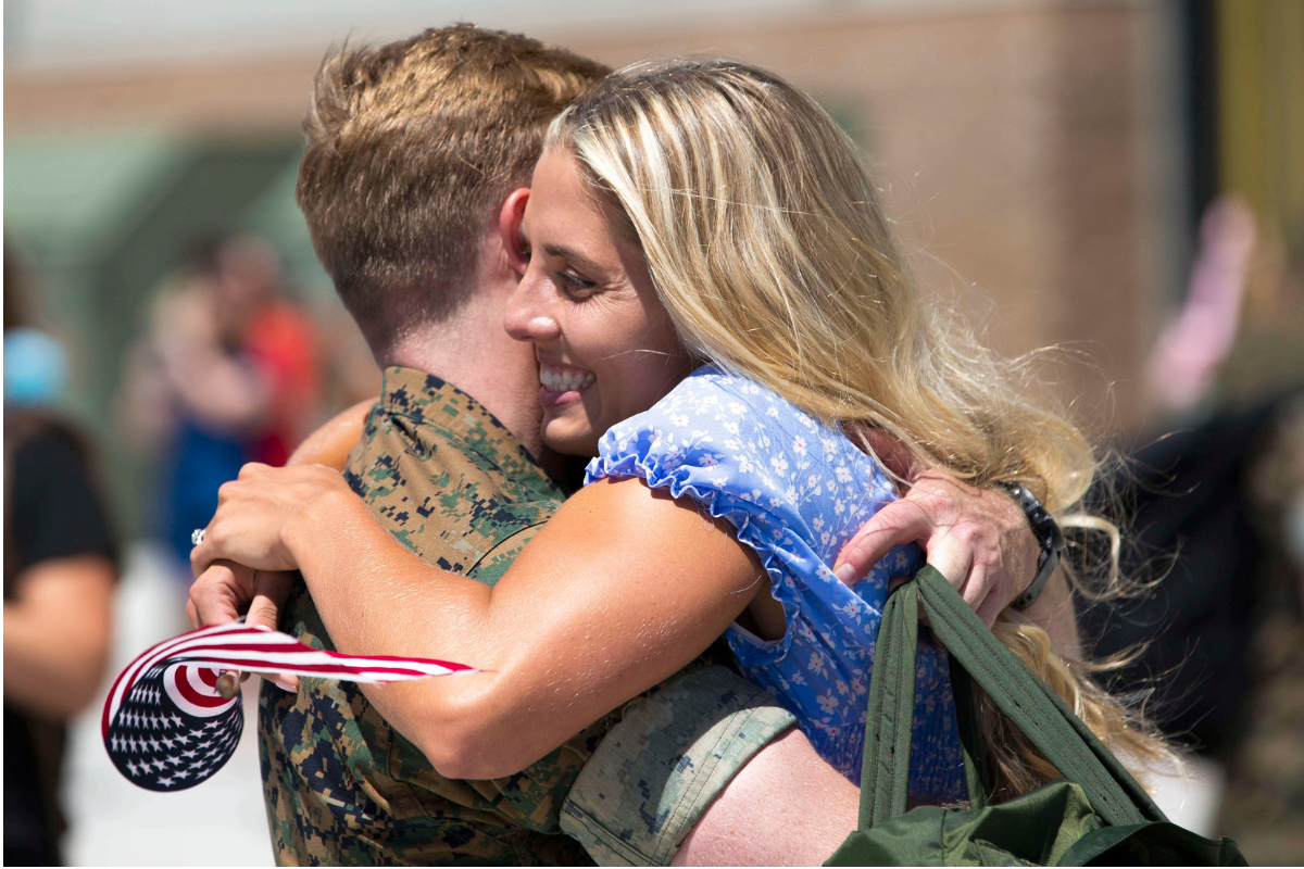 two children hug a service member